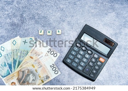 The inscription ZUS next to the calculator and Polish money. ZUS is a social insurance company