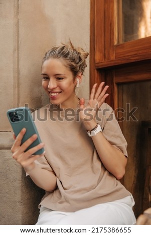 Picture of beautiful pretty woman have video call outdoors . Caucasian blonde girl smiling and looking at her smartphone in cafe 