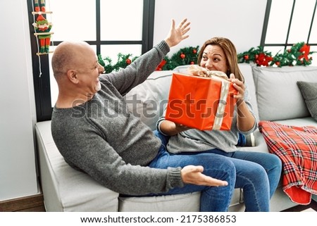 Couple in christmas celebration, woman giving a gift to a man