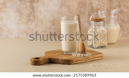 A glass of oat milk, a jug and oat flakes. The concept of alternative lactose-free dairy products. Copy space. Royalty-Free Stock Photo #2175389963