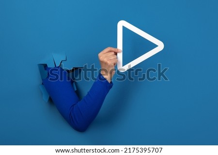 hand holding play button over blue background