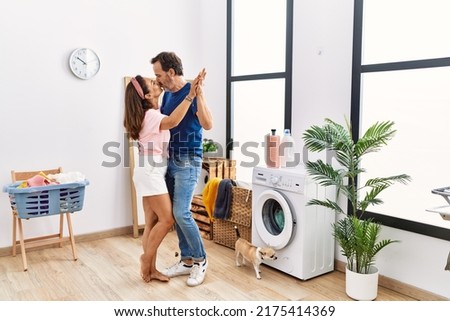 Middle age man and woman couple dancing and washing clothes at laundry room