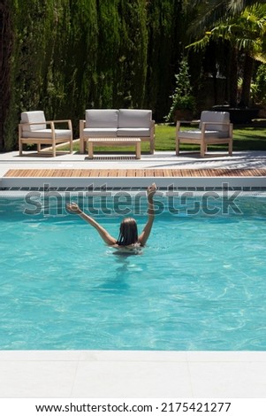 Vertical view of young unrecognizabel woman enjoying the refreshing time in the swimming pool in hot summer day