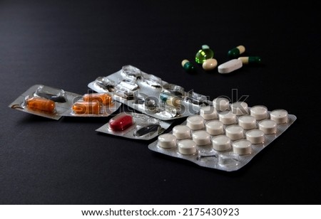 blister packs and medicial pills scattered on a black table