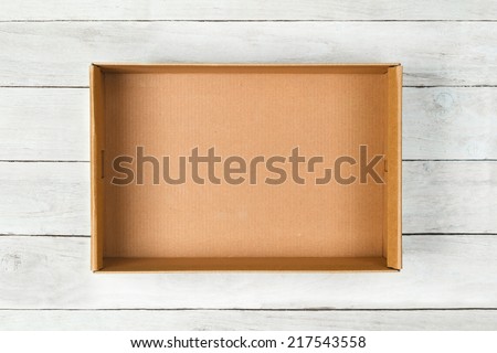Cardboard box on a white wooden background Royalty-Free Stock Photo #217543558