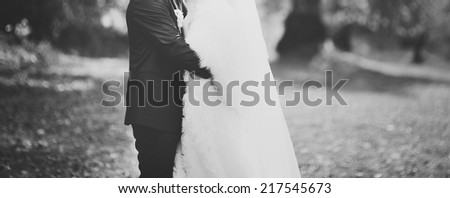 Black and white wedding picture. Newlywed couple holding hands,  