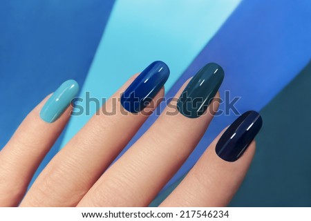 	  Blue manicure in light and dark colors of lacquer on a striped background. Royalty-Free Stock Photo #217546234