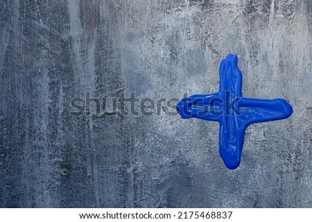 Blue plus sign on gray rough abstract background.