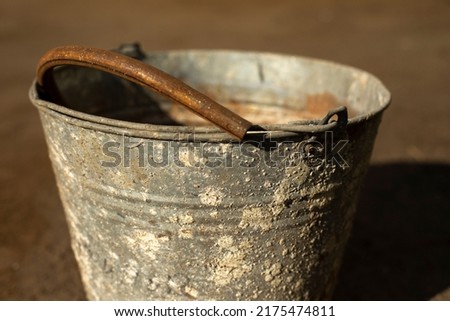 Old bucket of metal. Rusty bucket covered with lichen. Old item. Junk on street. Royalty-Free Stock Photo #2175474811