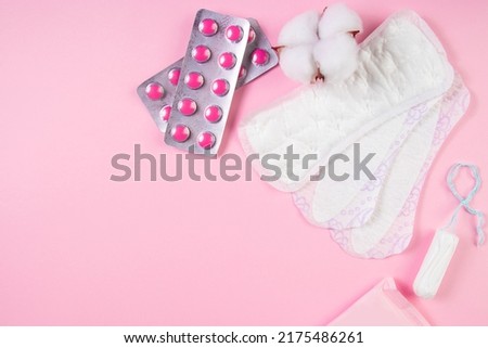 Set of feminine hygiene products for menstruation. Sanitary pads, tampons, pills on pink background. Womens health concept. Copy space.