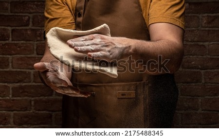 Clap hands of baker with flour. Beautiful and strong men's hands knead the dough make bread, pasta or pizza. Powdery flour flying into air.