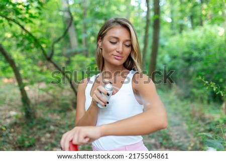 Woman applying insect repellent against mosquito and tick on her arms during hike in nature. Skin protection against insect bite Royalty-Free Stock Photo #2175504861