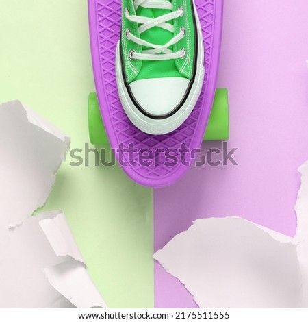 Pastel color trend. Penny board with a sneaker on green-pink background with torn paper. Concept art. Creative layout. Minimalism. Top view