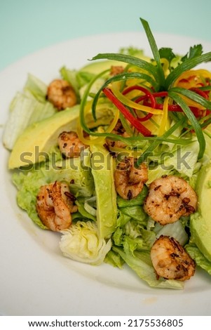 Thai spicy and tasty seafood and sausage salad in white dish on wooden table.