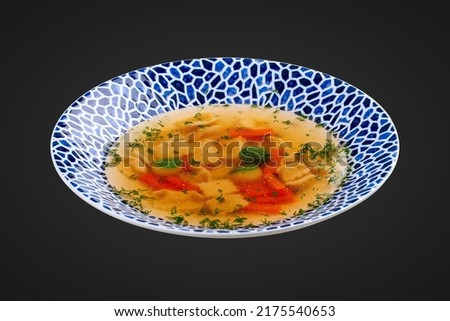 Soup consomme with vermicelli and vegetables. On a black background. Isolated