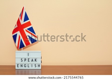 Text I speak English and flag of Great Britain, against background of cream colored wall wall, on the side there is an empty place for text. Education concept.