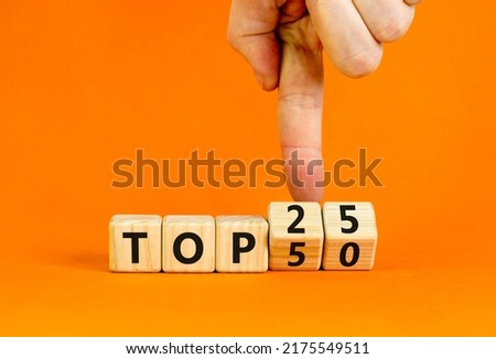 From Top 50 to 25 symbol. Businessman turns wooden cubes and changes concept words Top 50 to Top 25. Beautiful orange table orange background. Business and from Top 50 to 25 concept. Copy space.