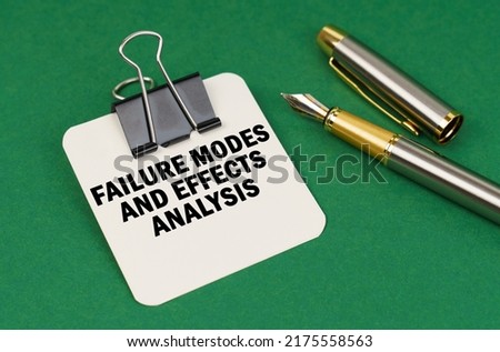 Business and industry concept. On a green surface, a pen and a sheet of paper with the inscription - Failure Modes and Effects Analysis Royalty-Free Stock Photo #2175558563