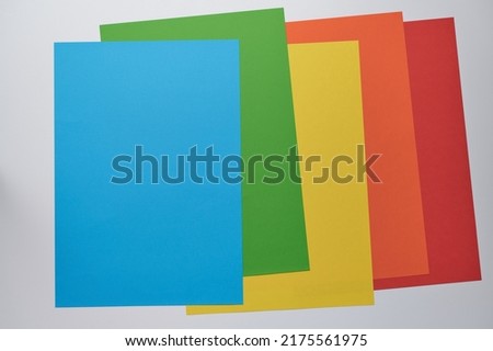 Image background of five sheets in different colors lie on top of each other, the top paper is blue, text free space