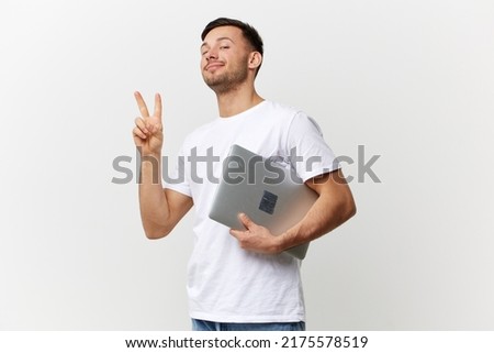 Happy cheerful tanned handsome man in basic t-shirt show v sign gesture hold laptop pc posing isolated on over white studio background. Copy space Banner Mockup. Electronics repair concept