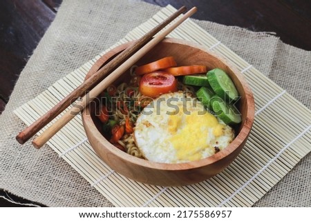 Tasty Fried Noodle with Fried Egg, sliced ​​tomato, chili and cucumber for extra