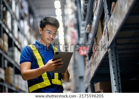 Warehouse Worker in safety suite using digital tablets to check the stock inventory in large warehouses, a Smart warehouse management system, supply chain and logistic network technology concept. Royalty-Free Stock Photo #2175596205