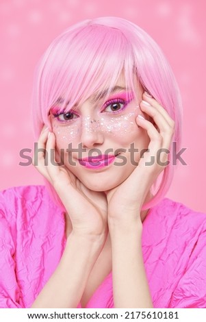 Girly pink style. Portrait of a pretty teenage girl with pink hair, pink makeup and cute shiny freckles. Asian anime style. Pink background.