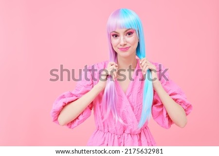 A lovely, smiling girl with colored purple-blue hair dressed in a pink dress poses on a pink background. Hairstyle, hair coloring. Make-up and cosmetics. 