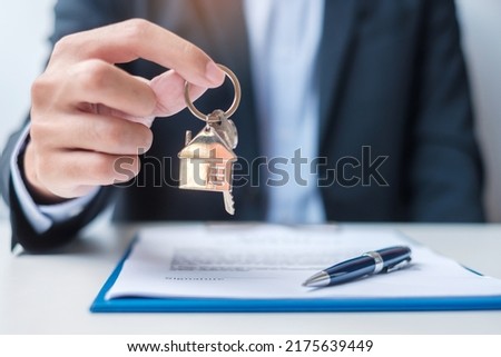 man holding home key during signing home contract documents. Contract agreement, real estate,  buy and sale and insurance concepts
