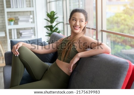 A fit beautiful asain woman in sportswear sitting and relaxing on sofa after workout, health and exercise concept Royalty-Free Stock Photo #2175639983