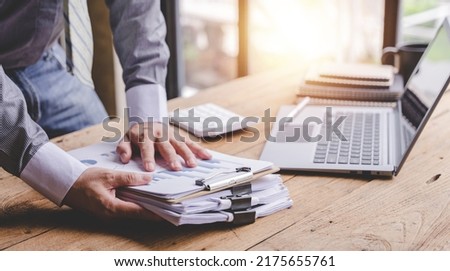 work from office A businessman works a bunch of paper files to find information on his desk at home. business report pile of unfinished documents Royalty-Free Stock Photo #2175655761