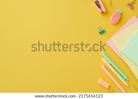 Back to school concept. Top view photo of colorful school accessories notepads pineapple shaped eraser stapler binder clips and pens on isolated yellow background with empty space