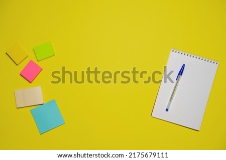 Notebook and pen on a yellow background. Top view with copy space. Stationery for school and office