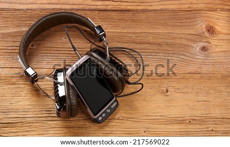 mobile phone with headphones and isolated screen on old wooden desk.