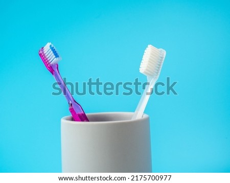 Toothbrushes in a glass with copy space on a blue background.