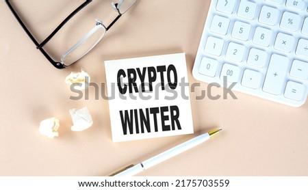 CRYPTO WINTER text on sticky with pen ,calculator and glasses on beige background