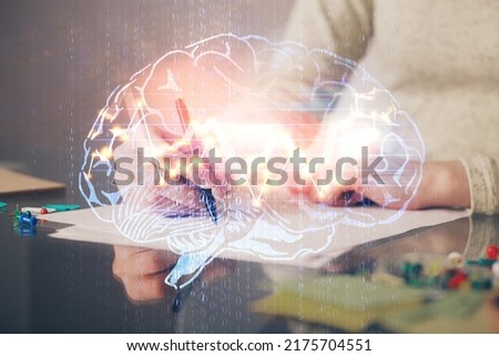 Double exposure of woman's writing hand on background with brain hud. Concept of learning.