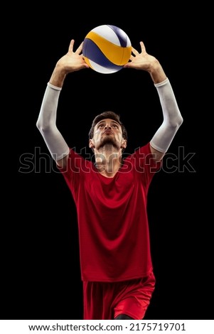 Portrait of young man, volleyball player in motion, training, bumping ball with fingers isolated over black studio background. Concept of sport, action, team game, active lifestyle, health, hobby, ad Royalty-Free Stock Photo #2175719701
