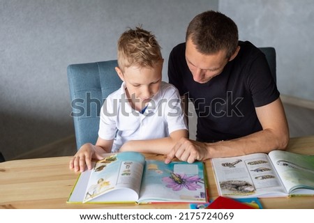 turn the page, look at pictures, read a book, drawings, flip through a page, home leisure, child and parent. boy, dad and son, home schooling, sitting at the table, lots of books