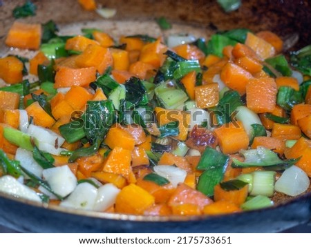 Carrots are fried in a pan along with leeks and garlic. Cooking food with smoke. Roasting vegetables. Ingredient for the dish.
