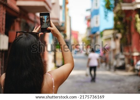 Young female tourist is exploring new city making photo on smartphone
