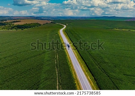truck driving on asphalt road along the green fields. Aerial view landscape. drone photography. cargo delivery