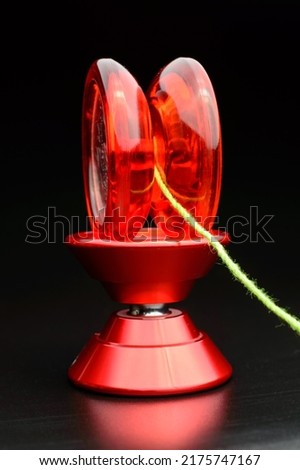 Red plastic yo-yo toy on the top of another aluminium yo-yo isolated on dark Background with a pretty green rope attached to it.