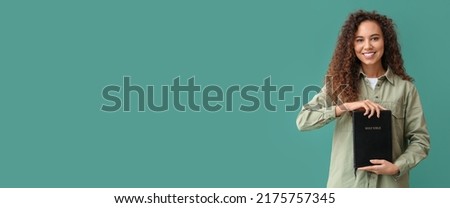 Young African-American woman holding Holy Bible on green background with space for text