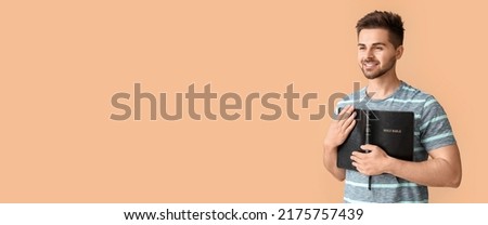 Young man with Bible on beige background with space for text