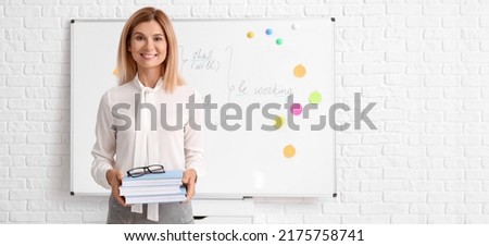 Beautiful English teacher with books in classroom