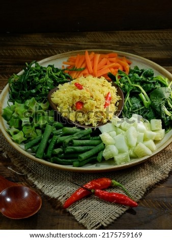 Indonesian traditional food urap sayur is a salad dish of steamed various vegetables mixed with seasoned and spiced grated coconut for dressing served on plate. Dark background. selective focus.
