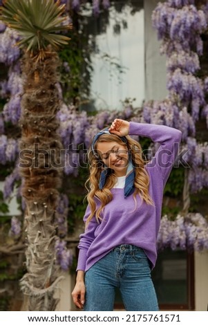 A young beautiful blonde woman near a flowering wisteria