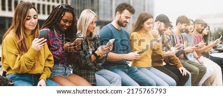 Gen z diverse people using cellphones sitting on a bench outdoors, panorama. Lifestyle concept with multiracial men and women using smartphones. Gadget users crowd Royalty-Free Stock Photo #2175765793