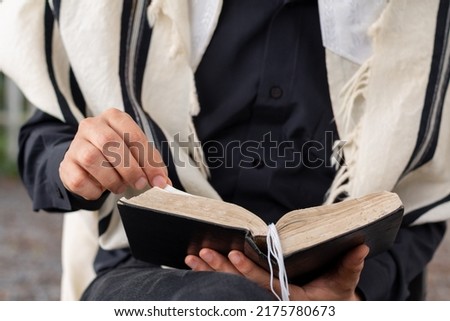 Close-up of Jewish man wearing tallit reading the siddur on Shabbat. Royalty-Free Stock Photo #2175780673
